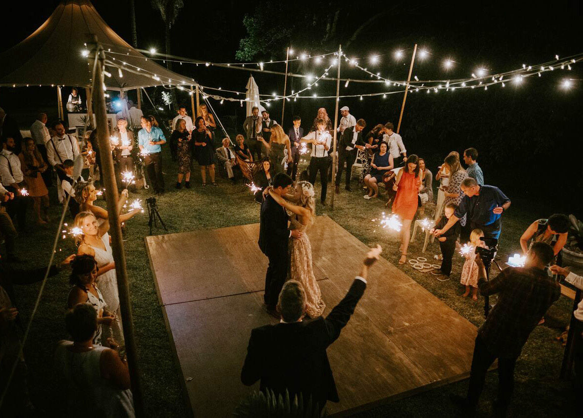 Bride and groom sharing their first dance outdoors under vintage fairy lights at Bangalow Guesthouse