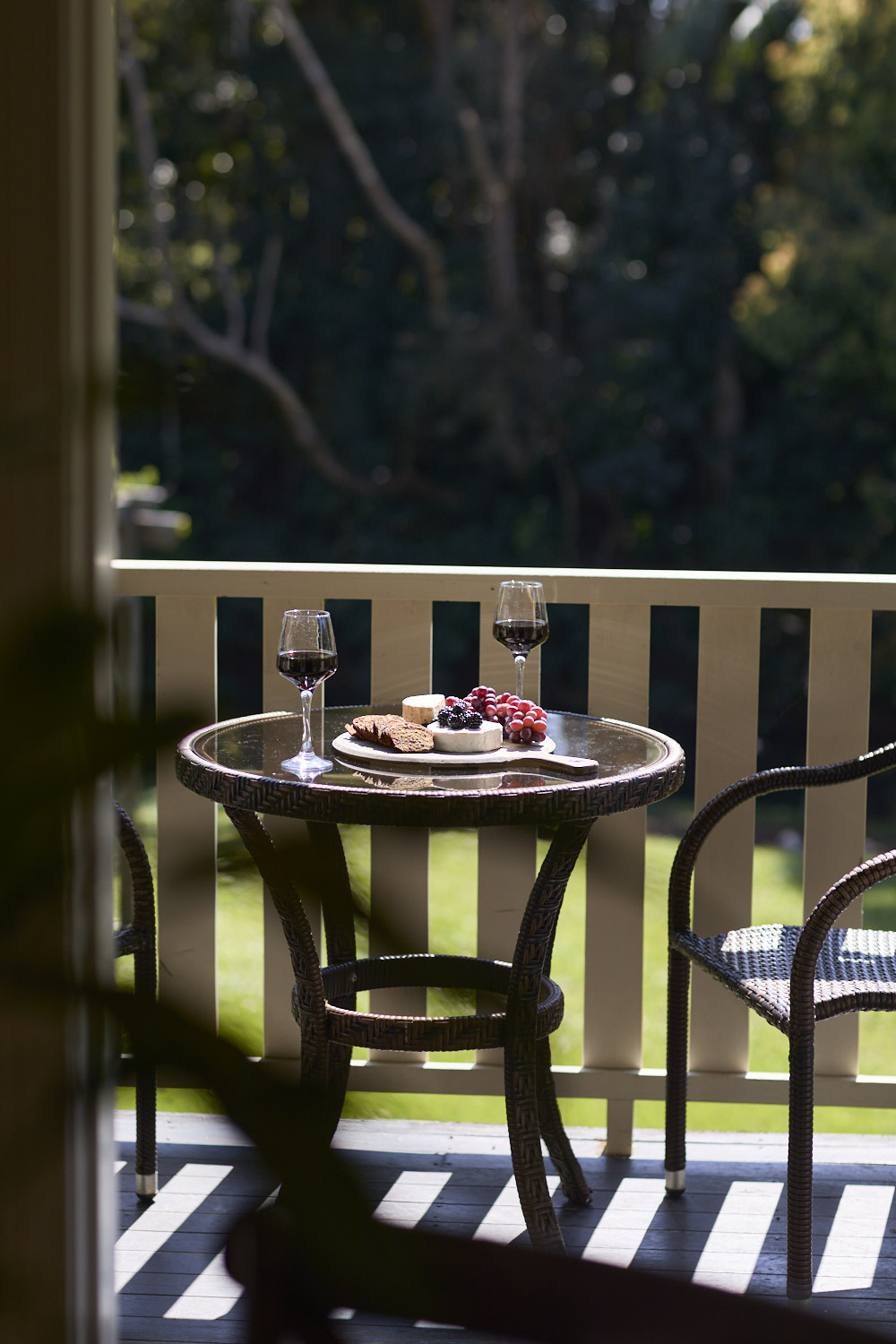 Charming bistro-style seating on the balcony at The Bangalow Guesthouse overlooking lush heritage gardens