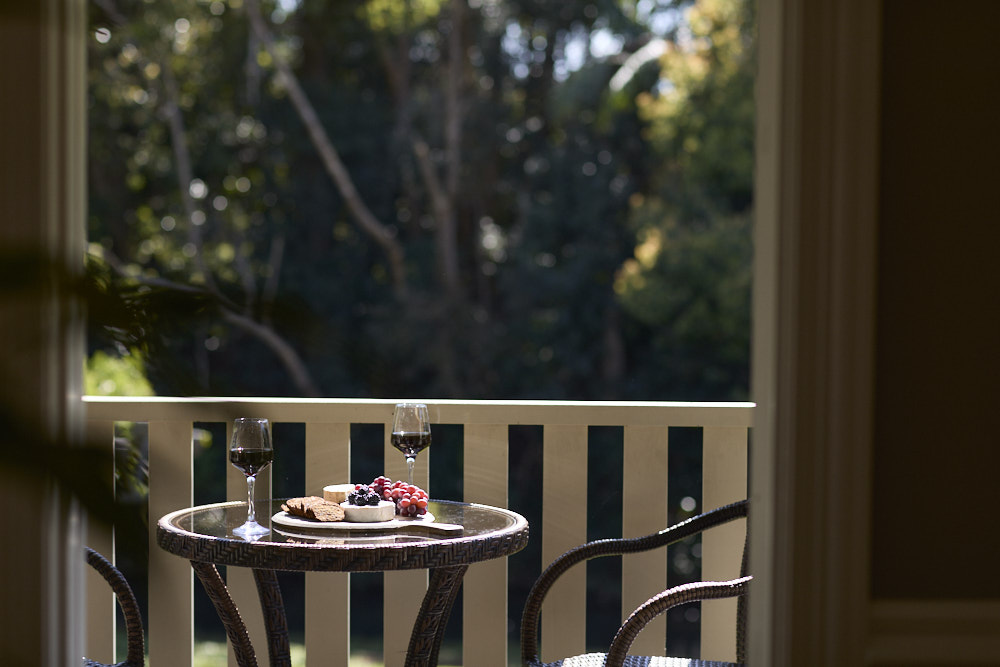 Charming bistro-style seating on the balcony at The Bangalow Guesthouse overlooking lush heritage gardens